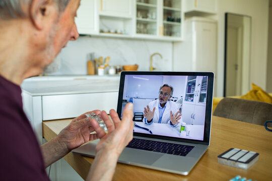 Senior patient consulting doctor via telemedicine at kitchen table