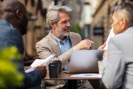 Business team discussing reports at outdoor cafe
