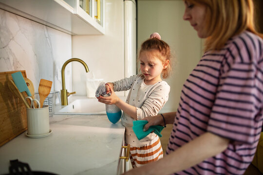 Parent and child cleaning kitchen countertop at home