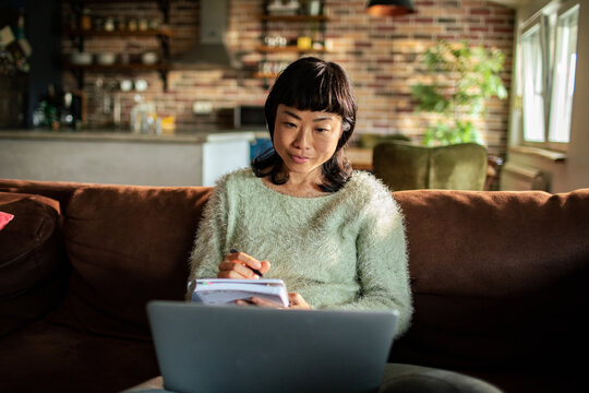 Woman studying with laptop on sofa at home