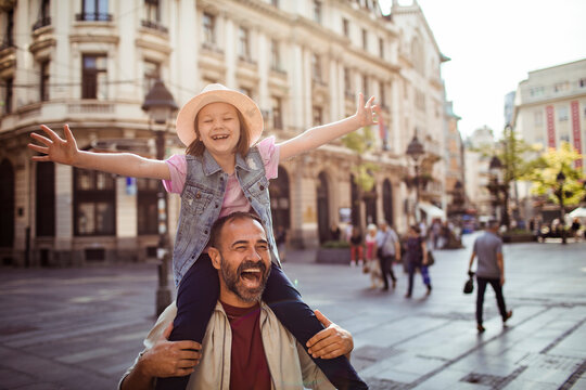 Happy father carrying daughter on shoulders in city street