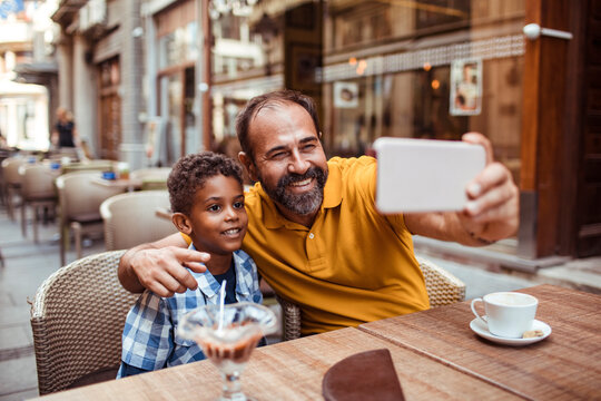 Smiling father and son taking selfie at outdoor cafe