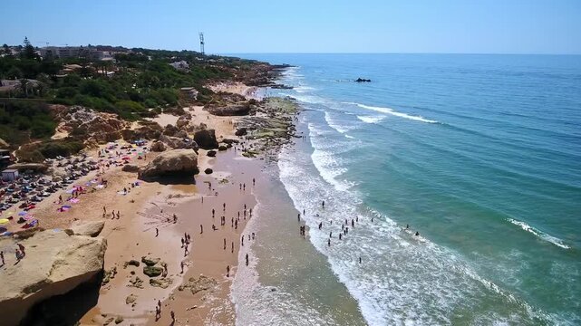 Sunny summer day at gale beach in albufeira, portugal, with tourists swimming in the atlantic ocean and sunbathing on the sandy shore surrounded by beautiful rock formations