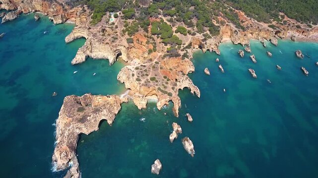 Stunning aerial view flying over the ponta da piedade headland near lagos in portugal, revealing the beautiful grottos, natural rock arches, and clear turquoise waters of the atlantic ocean