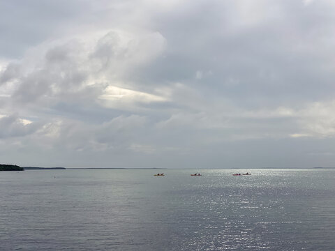 Light breaks through the clouds and lights up the waters of Biscayne Bay off Elliott Key where a few kayakers are paddling back to land