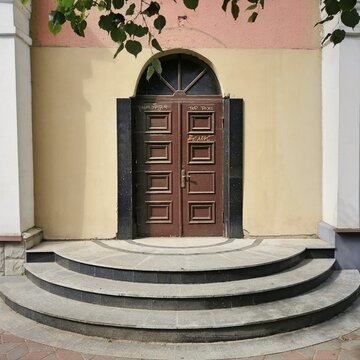 Old wooden double door with stone stairs and semi-circular porch