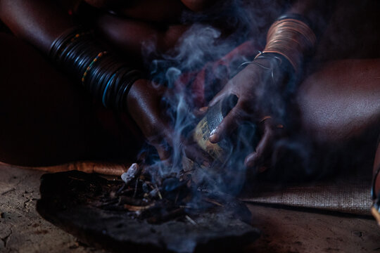Himba woman performing traditional smoke ritual in Namibia
