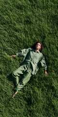 Naklejka premium Top view of a woman lying on tall green grass in a matching outfit for lifestyle wellness background and banner design