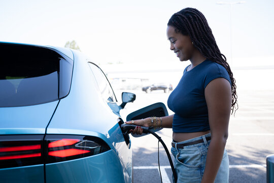 A African American woman charges an electric vehicle