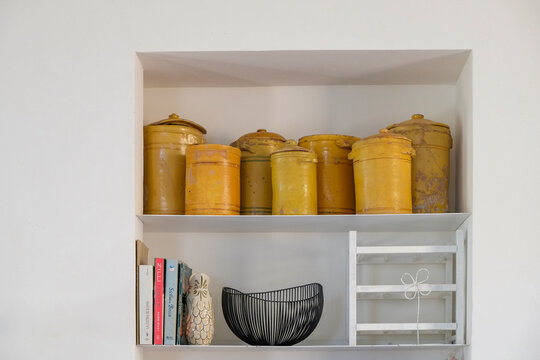  Yellow ceramic storage jars displayed on a shelf