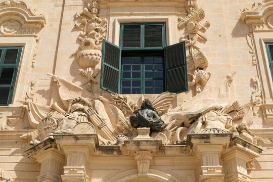 Ornate carved facade detail with green shuttered window, Malta,