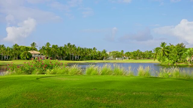 View of a beautiful golf course with green grass and lakes in the park. Tranquil golf course scenery. Luxurious lifestyle. Rich green lawn and beautiful tropical landscape.