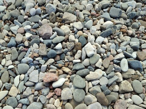 Colorful pebbles and stones scattered on a beach surface  