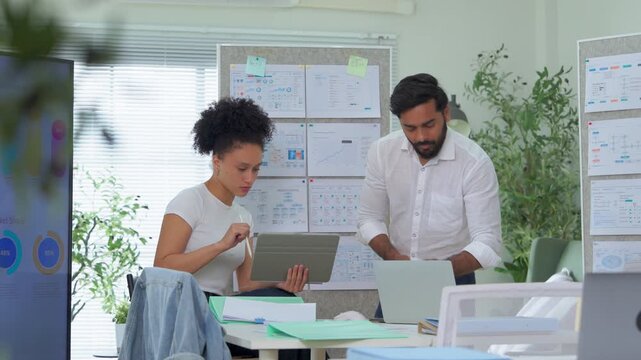A smiling colleague reviews content on a tablet with a supportive coworker pointing at the screen, both engaged in a positive collaboration a bright, upbeat scene of teamwork, mentoring, and workplace