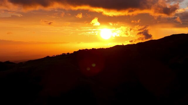 Golden sun setting behind silhouetted mountain landscape