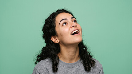 Obraz premium Happy Young Woman Looking Up with Amazement Isolated on Green Background