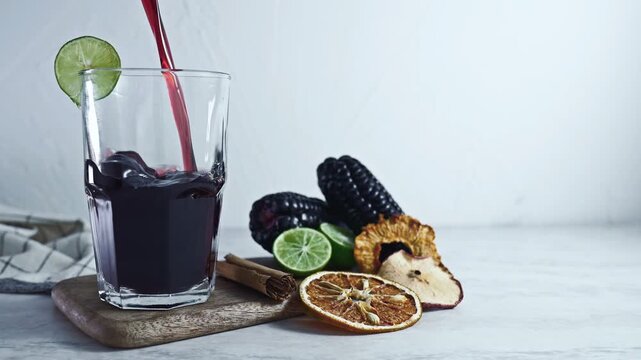 Pouring Peruvian Chicha Morada Purple Corn Drink with Lime and Cinnamon