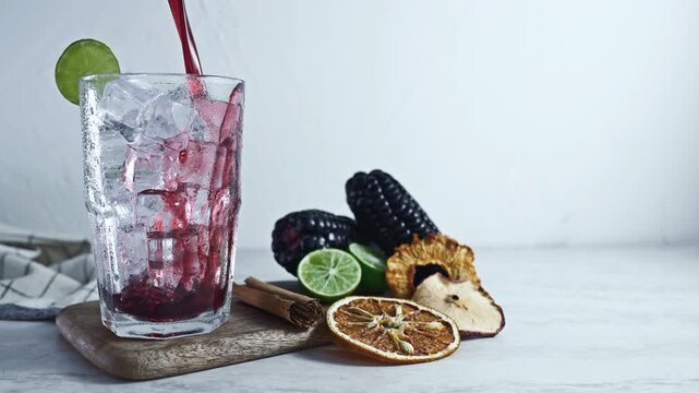 Pouring Peruvian Chicha Morada Purple Corn Drink with Lime and Cinnamon