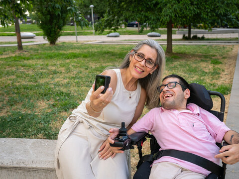 Mother and adult son with disability smiling while taking a selfie with an action camera