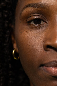 African American woman showing right half of face in studio featuring cheek studs and gold hoop