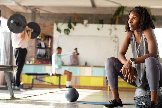 Diverse group in athletic wear working out in studio using 10 lb medicine ball, copy space