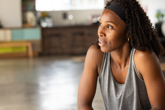 African American woman sitting in bright studio wearing gray tank and black headband