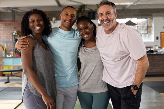 Diverse friends smiling and posing in loft gym wearing sportswear near exercise bench