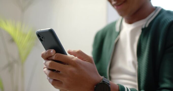 Man is holding phone thumbs poised then tapping and scrolling in living area while reading text