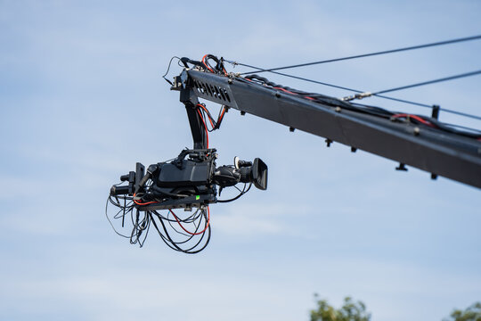 Television broadcast camera rig attached to an industrial crane jib arm operating in an outdoor media production environment