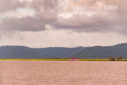 Regional passenger riverboat navigating the Amazon River against a backdrop of forested hills
