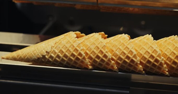 Precise robotized manipulator replaces crusty wafer cones at ice cream factory closeup. Confectionery shop equipment carries fragile food products efficiently