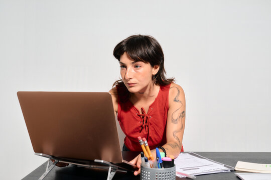 A focused woman works intently on her laptop. She concentrates deeply, her gaze fixed on the screen as she types.