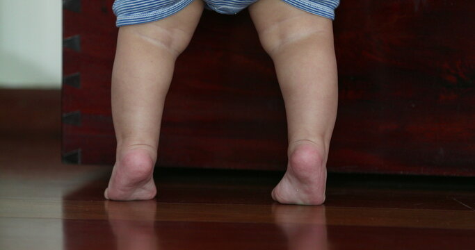 Baby little feet on tip toes. Toddler reaching and standing up