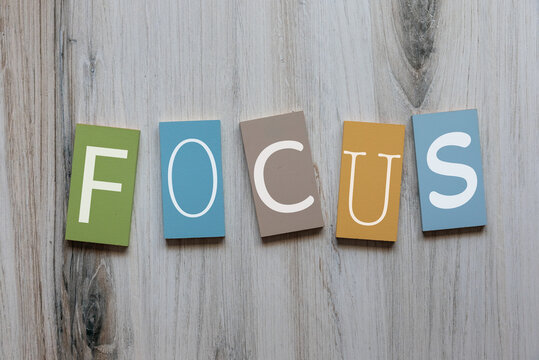 The word focus in white on pastel wooden tiles flat lay background 