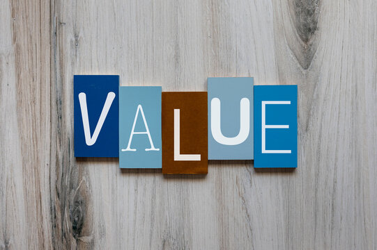 The word value in white on wooden tiles concept background.