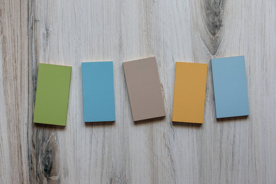 Photo of blank wooden vertical rectangles light pastel colors laying on wood background. Flat lay graphic resource. 