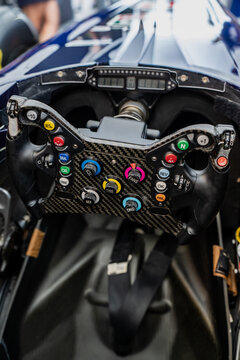 Detailed technical view of a formula motorsport vehicle interior showing carbon fiber steering wheel controls, digital dash, and monocoque tub