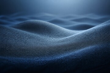 Fototapeta premium Deep blue waves ripple with fine granular texture. Soft light glows from above, casting gentle shadows. The surface shimmers with subtle sparkle and depth. Ideal for serene, abstract