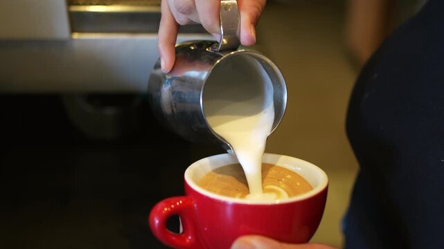 Barista creating latte art with steamed milk