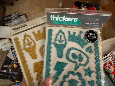 Phoenix, Arizona - August 1, 2026: Hand holds packages of Thickers chip board scrapbooking stickers by American Crafts