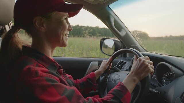 Young woman in red shirt steers 4x4 off road car in the wild on sunset