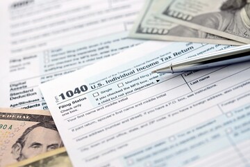 Obraz premium 1040 Individual Income tax return form and pen with dollars money bills on accountants table
