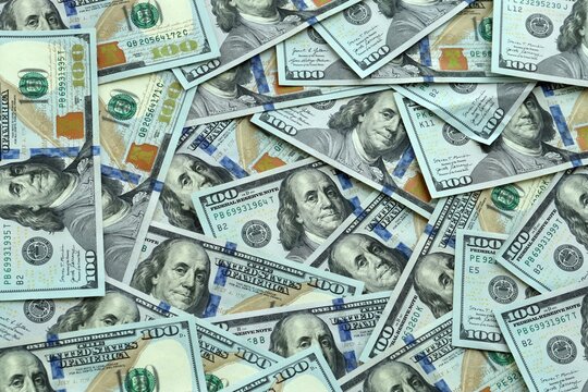 US one hundred dollar money banknotes pile on table. United States bills of USD currency close up