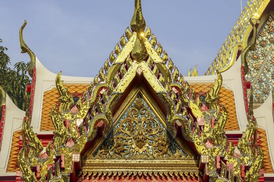Golden mosaic ornaments rise like flames to heaven carried by Chofa and Bai Raka on the ornate pediment of the Wat Pho Temple, a brilliant detail of Thai religious architecture, Wat Pho, Bangkok, Thailand