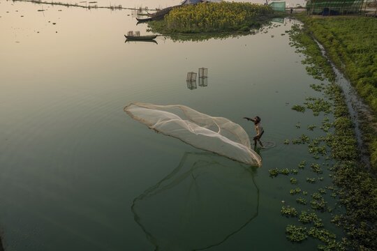 Fishermen on Taung Tha Man Lake throw out a fishing net for sunrise, reflection in the water, Thaung Tha Man Lake, Mandalay, Myanmar