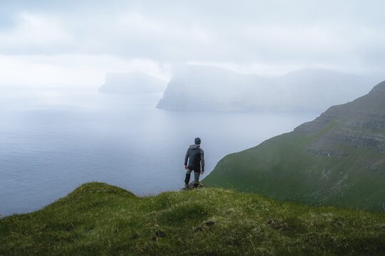 Person standing on the mountain looking at the village of Mikladalur, Kalsoy, Faroe Islands