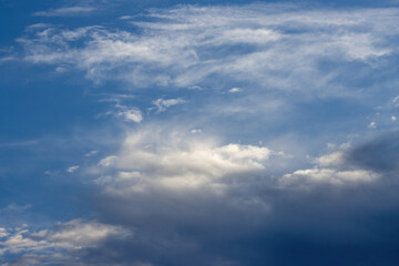 Fototapeta premium Beautiful morning clouds of an approaching atmospheric front, illuminated by sun rays, signalling changing weather from sunny to rainy conditions.