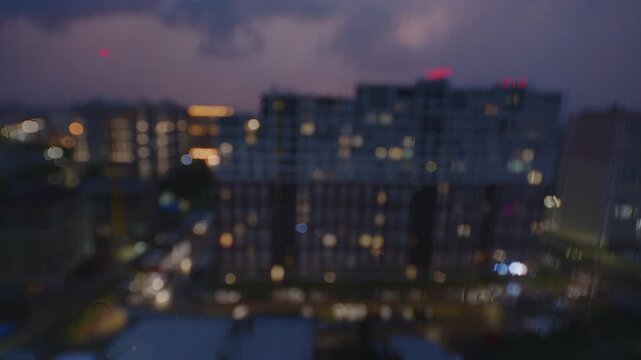 Night rainy city as seen through the wet window surface with water distortion