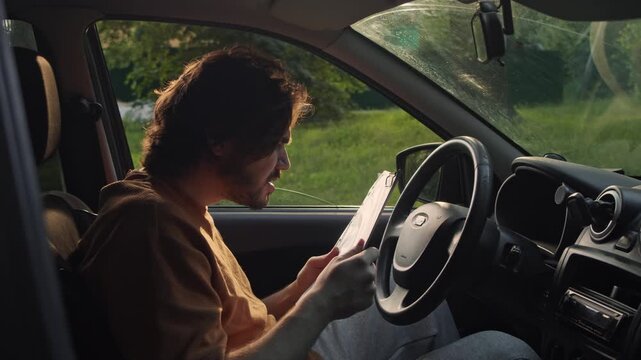 Frustrated driver throws insurance documents out of the car window after reading them. He is ready to leave following an upsetting paperwork issue.