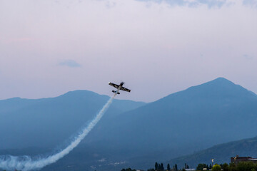 Fototapeta premium Aerobatic Plane Performing Smoke Trail Over Mountains At Air Show In Chilliwack, BC, Canada